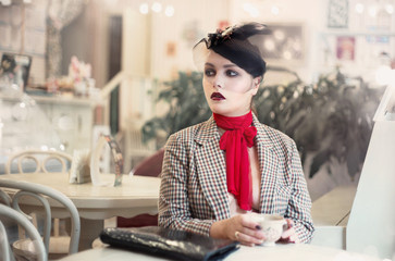 Fototapeta premium Portrait of a young beautiful woman in vintage style in a cafe.