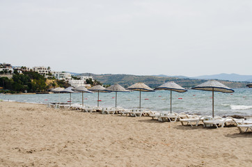 Fototapeta na wymiar Rows of empty sun loungers and umbrellas on the beach. Camel Beach in Turkey.