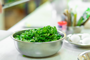Cook in the kitchen cuts greens close up