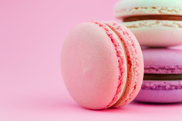 Three macaroons on bright pastel pink background. Macro side view concept, copy space. French dessert