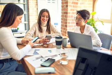 Beautiful businesswomen smiling happy. Sitting with smile on face working using smartphone and laptop at the office