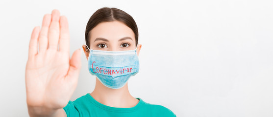Portrait of a woman in medical mask with coronavirus text and showing stop gesture at white background. Coronavirus concept. Respiratory protection