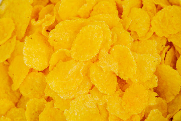 Corn flakes are scattered on the table as a background and texture.