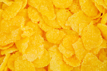 Corn flakes are scattered on the table as a background and texture.