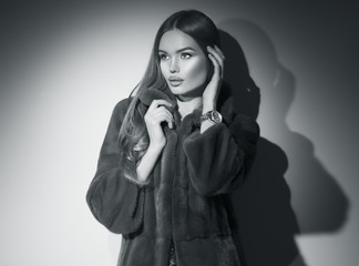Beauty Fashion Model Girl in Mink Fur Coat black and white portrait. Beautiful Woman in Luxury Brown Fur Jacket posing in studio. Expensive wear, Winter Fashion, elegant style
