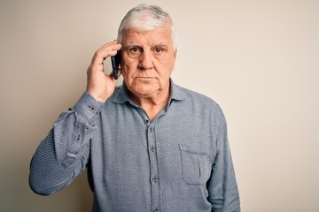 Senior hoary man having conversation talking on the smartphone over white background with a confident expression on smart face thinking serious