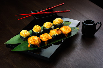 Baked rolls on the board with sauce and red chopsticks