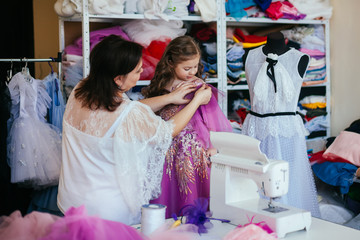 Seamstress fashion designer takes a new order in his studio. Makes measurements of dresses for girls