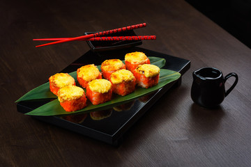 Baked rolls on the board with sauce and red chopsticks