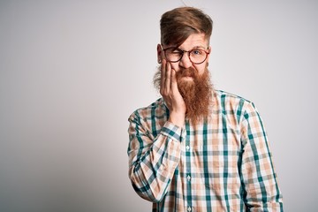 Handsome Irish redhead man with beard wearing glasses and hipster shirt thinking looking tired and bored with depression problems with crossed arms.