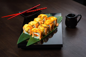 Baked rolls on the board with sauce and red chopsticks