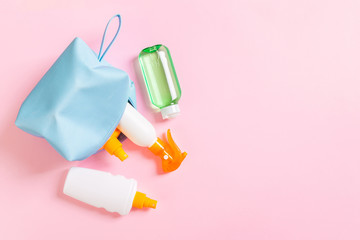Top view of female cosmetics bag full of suncream spray, sunsreen, sunblock and body lotion and spf cream on pink background with copy space. Directly above. Bright summer concept