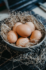 eggs in a plate with straw on a black surface