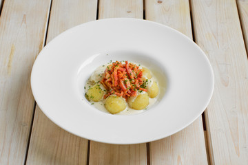 Potato dumplings with bacon on wooden table