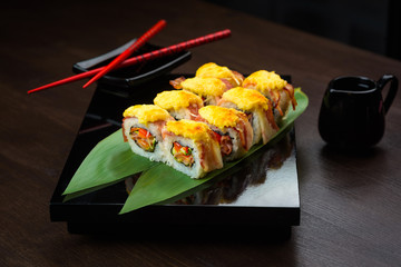 Baked rolls on the board with sauce and red chopsticks