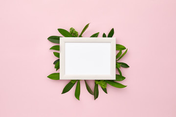 photo frame decorated with green leaves on pink pastel background. empty space for text. mock up with copy space. Flat lay