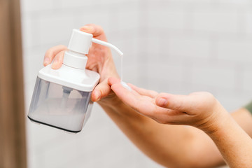 Female hands hold a dispenser with liquid soap or cream for moisturizing. Skin care and cosmetics.