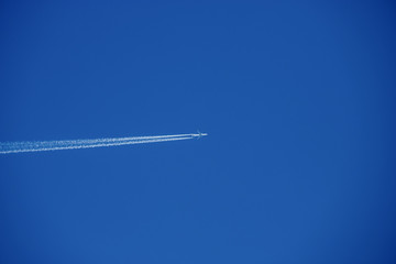 Plane flys very high in the blue coudless sky