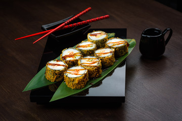 Baked rolls on the board with sauce and red chopsticks