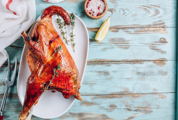 Roasted rooster with spices, lemon and thyme on white dish on rustic wooden background. Healthy food. Top view