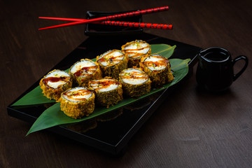 Baked rolls on the board with sauce and red chopsticks