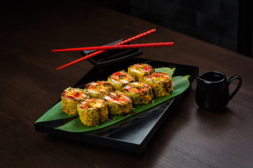 Baked rolls on the board with sauce and red chopsticks