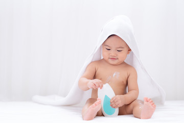 Asian cute baby wearing white towel after taking a shower applying moisturizing cream baby...