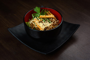 Noodles wok with chicken in a plate on a wooden table