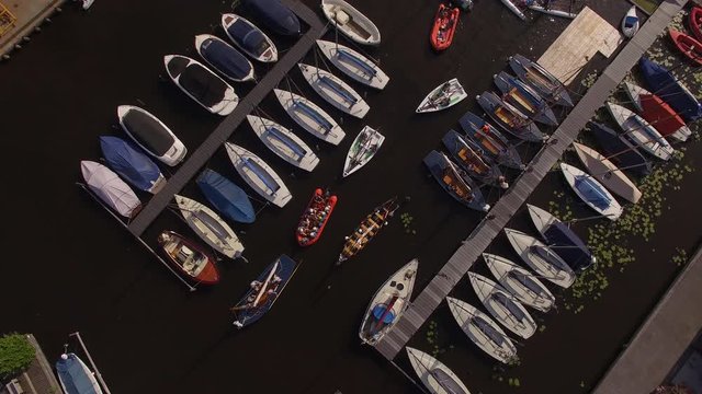 Cinematic drone shot of some boats gliding trough the harbor from above in the Netherlands