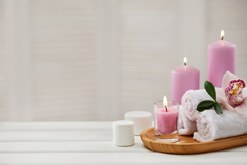 Spa products with aromatic candles, orchid flower and towel on white wooden table. Beauty spa...
