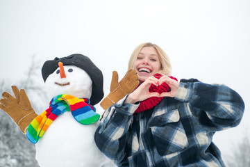Happy smiling girl make snowman on sunny winter day. Winter emotion. Outdoor portrait of winter girl in cold sunny winter weather in park.