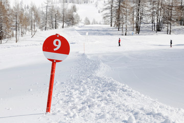 A red ski slope with number 9. Ski piste in the alp mountains. 