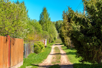 A typical street in the suburban areas in Russia with a dirt road