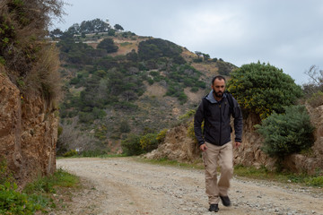 Naklejka premium Man walking along a Ceuta road with the lighthouse in the background and the cloudy sky