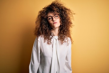 Young beautiful brunette woman with curly hair and piercing wearing shirt and glasses Relaxed with serious expression on face. Simple and natural looking at the camera.