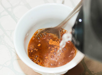 A Cup of cocoa or coffee is filled with boiled water.