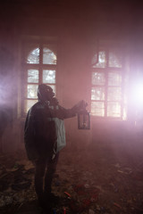 Dramatic portrait of a woman wearing a gas mask in a ruined building.