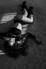 Beautiful girl in top, panties and high-heeled boots posing in the studio while laying on the concrete floor - black and white photography