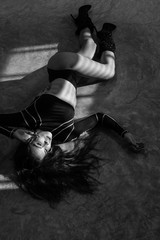 Beautiful girl in top, panties and high-heeled boots posing in the studio while laying on the concrete floor - black and white photography