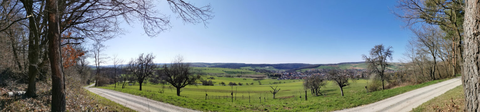 Grüne Landschaft mit Dorf Eschau unter blauem Himmel im Panoramaformat