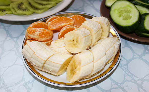 On a light saucer, a banana is cut into circles and tangerine slices are sprea