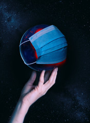 A hand holds the globe with a medical mask during an epidemic of Covid 19 or coronavirus worldwide. Concept
