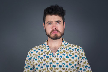 Obraz premium Beautiful face of sad man crying desperate and depressed with tears on his eyes suffering pain and depression isolated on grey background in sadness facial expression and emotion concept.