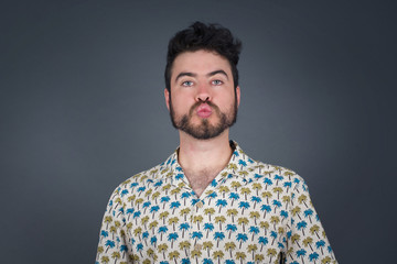 Attractive light haired male rounds lips, wears casual clothes, looks directly into camera,...