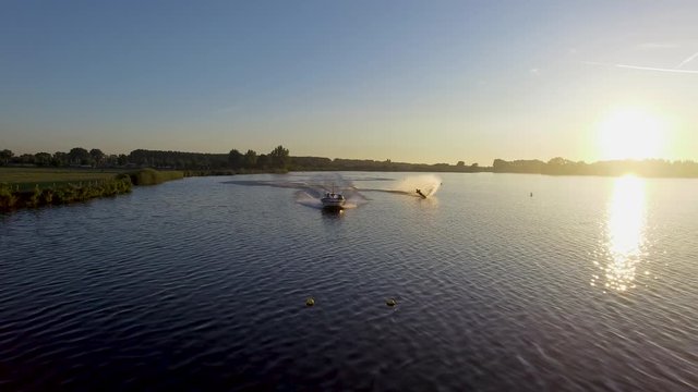 Speedboat with a mono waterskier behind it during a beautiful sunrise in the Netherlands