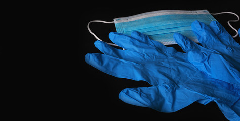 Blue medical sterile mask and blue sterile gloves isolated on a black background.