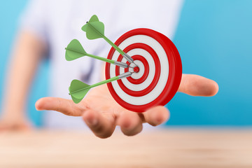 hand holding a target with darts hitting the center over white background. Concept of .