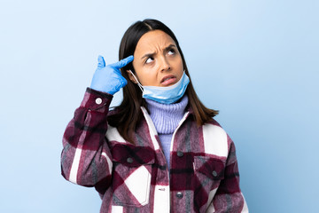 Young brunette mixed race woman protecting from the coronavirus with a mask and gloves over...