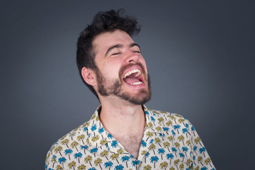 Joyful European man having fun and laughs at good joke or sings wears casual clothes, standing against gray wall. Happy woman with long hair poses inddoors.