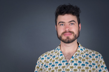 Close up studio shot of handsome young mixed race man model with curly dark hair looking at camera with charming cute smile while posing against white blank copy space wall for your content